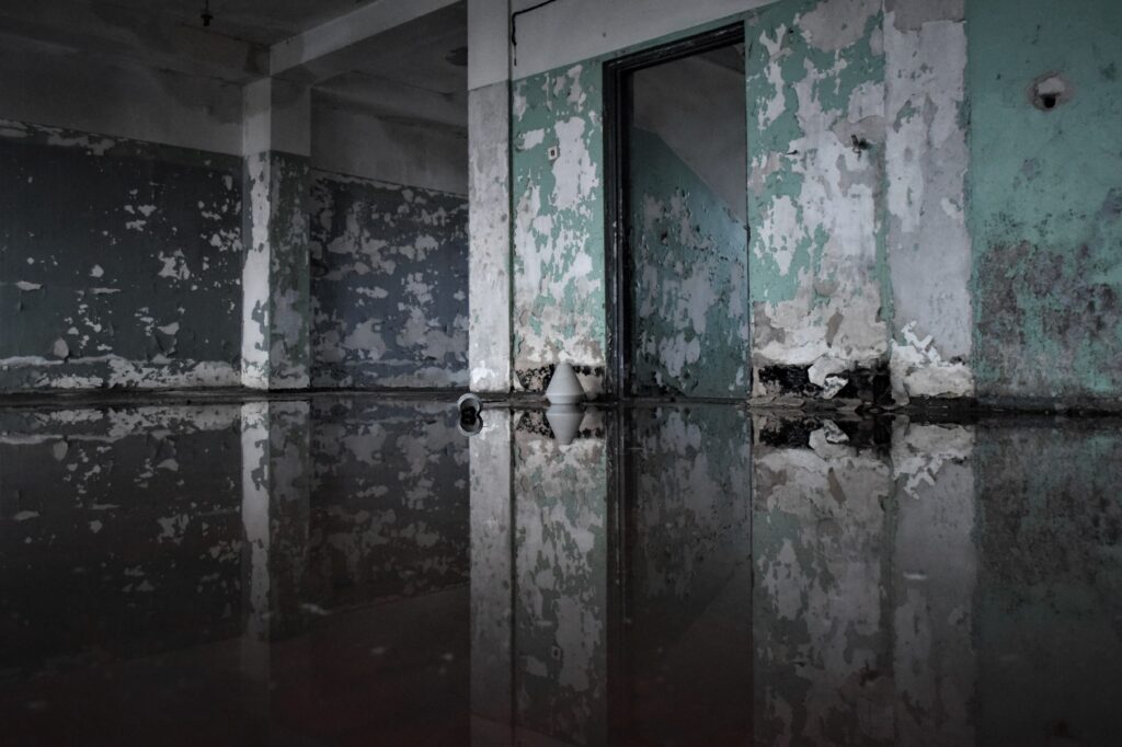 Flooded abandoned room with reflective water on floor showing water damage